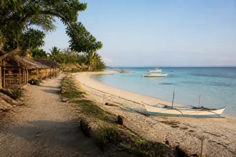 Early-morning view of Langub (North) Beach on Malapascua with pale sand, shallow water and small boats