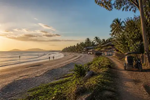 Wide west‑facing sandy shoreline of Long Beach, San Vicente at golden hour with few people