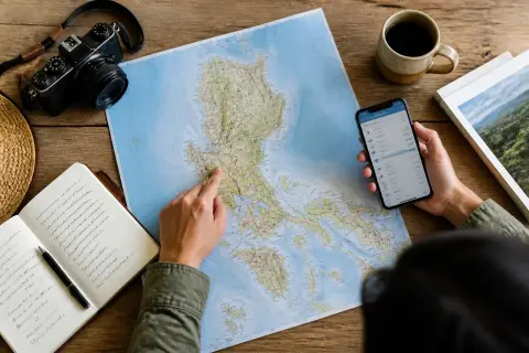Traveler planning a Luzon trip over a printed map with notes and a phone