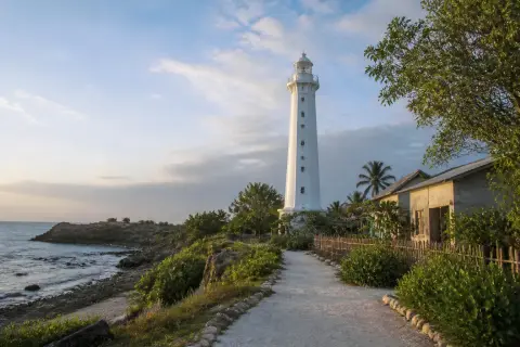 White Malapascua lighthouse above village path and rugged northwest coast