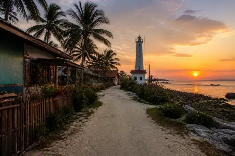 Sandy village lane toward Malapascua lighthouse and western coast at sunset