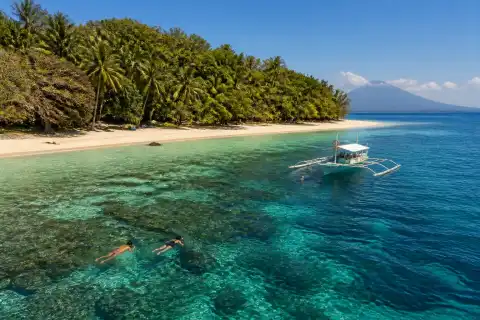 Mantigue Island white-sand beach, forested center and snorkelers in clear water