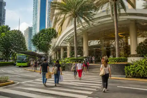 Market! Market! mall entrance in BGC with shoppers and a nearby bus pickup area