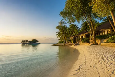 Mithi Resort private white-sand beach with Dream Islet and villas at sunset
