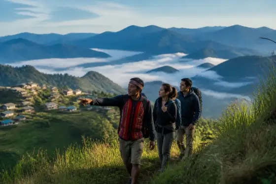 Hikers on a grassy ridge with layered mountains near Sagada