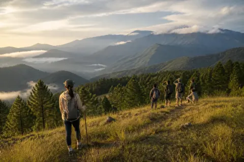 Hikers on a grassy ridge above pine forest with distant Cordillera mountains near Mount Ampacao, Sagada