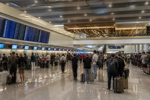 Wide interior view of NAIA Terminal 3 departure concourse with passengers and check‑in counters