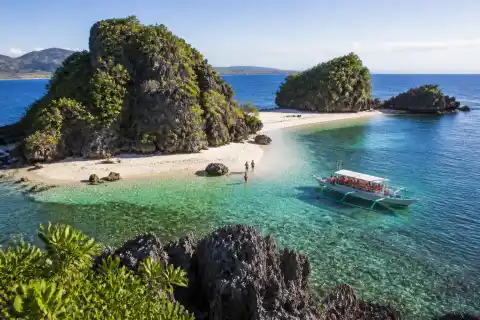 Small rocky islands and a boat near a white‑sand shore at Once Islas, Zamboanga
