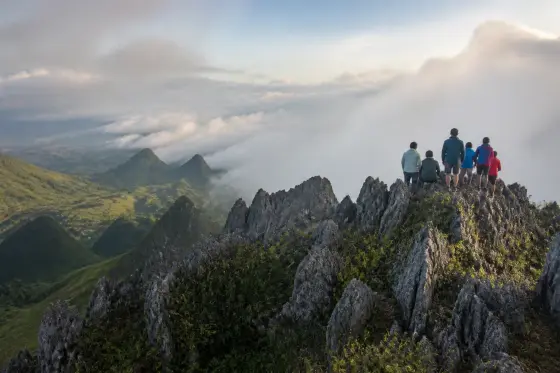 Hikers on Osmeña Peak's rocky ridges above Mantalongon highlands with low cloud