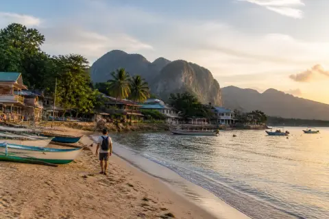 Public Palawan beach with local boats and village waterfront at sunset