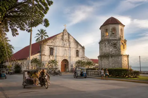 Panglao Poblacion plaza with Saint Augustine Church and coral-stone watchtower at sunset