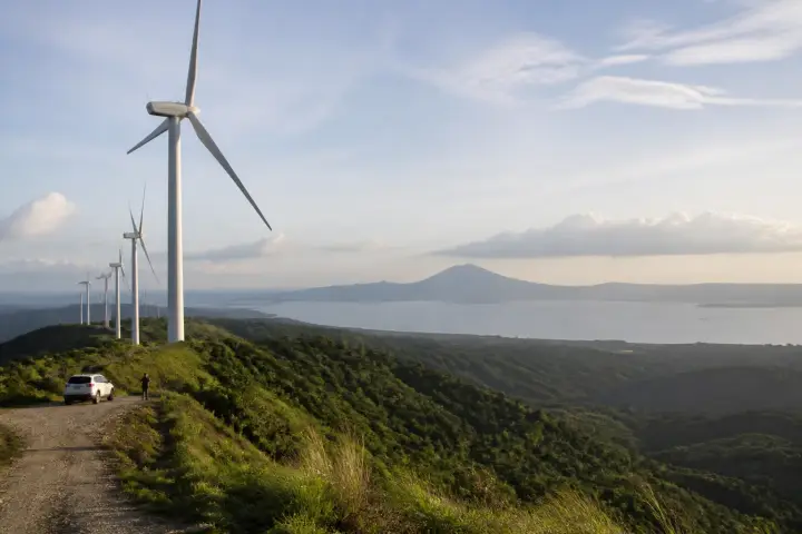 Wind turbines on rolling hills with Laguna de Bay in the background