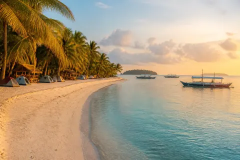 Punta Sebaring’s long white‑sand beach with palms and a simple campsite on Bugsuk Island