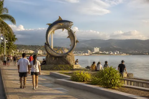 Visitors strolling the Queen Tuna Park waterfront with tuna arch and Sarangani Bay at dusk