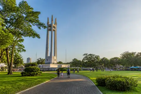 Quezon Memorial Circle monument and park lawns with people walking