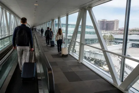 Passengers with luggage crossing an enclosed skybridge between NAIA Terminal 3 and Newport City