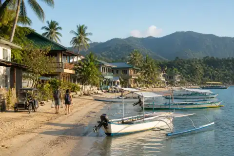 Port Barton village beach with anchored bancas and palm trees