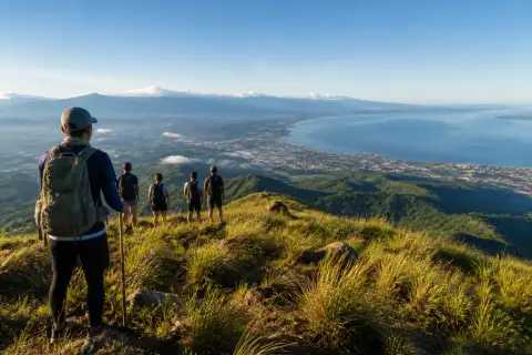 Hikers on a grassy ridge with panoramic view of General Santos and Sarangani Bay