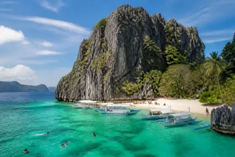 Limestone karst, small beach and outrigger boats at Shimizu Island, Bacuit Bay