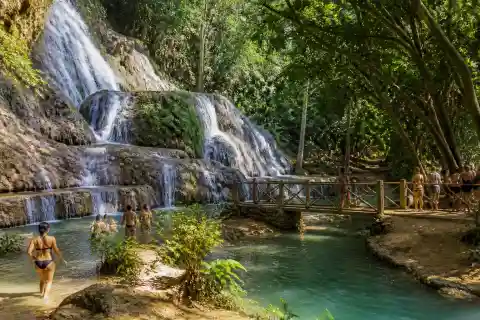 Multi‑tier waterfall and cold spring with visitors on a rustic path