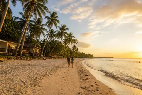 Paliton Beach at sunset with coconut trees and calm sea in Siquijor
