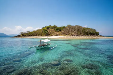 Sombrero Island with a small boat anchored offshore in calm morning sea