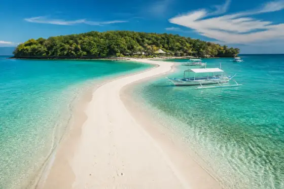 Sumilon Island sandbar curving into clear turquoise water with boats near shore