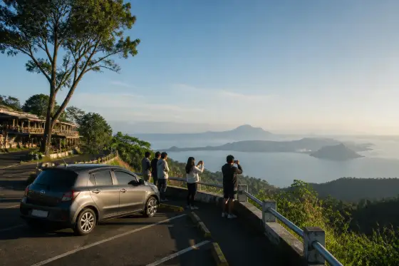Parked car at a Tagaytay ridge viewpoint overlooking Taal Lake and Volcano Island in morning light