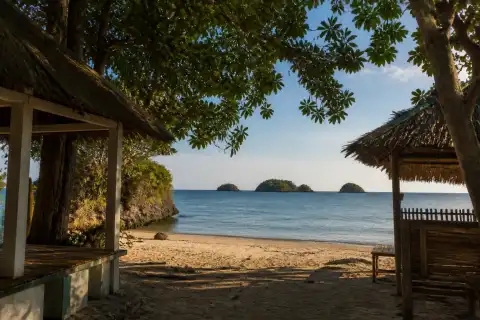 Shaded Tatlong Pulo Beach shoreline with three offshore islets visible