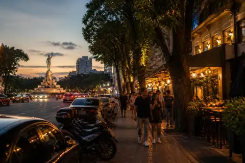 Tomas Morato Avenue at dusk with restaurants, pedestrians and the Scout rotunda in the distance