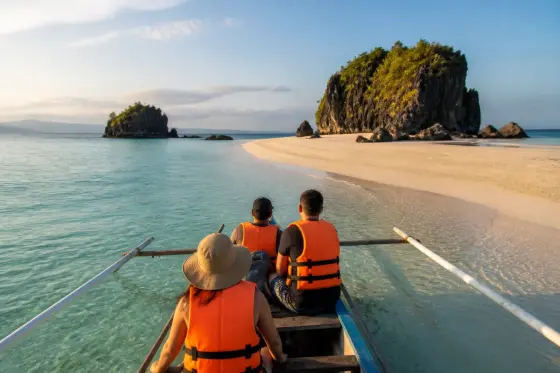Small boat approaching a pale sandbar and limestone islets in the Visayas