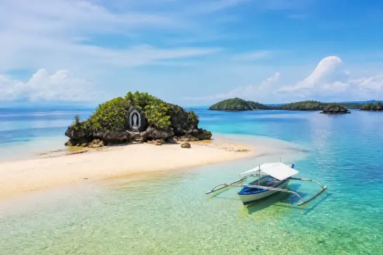 Pale-sand islet with shallow turquoise sea and dark rock formations near Guimaras