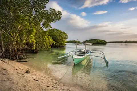 Mangrove-edged lagoon with pale sand and a small pumpboat at Bantayan Island