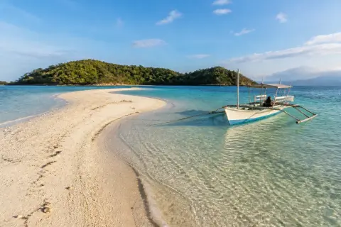 Sandbar with pale sand, turquoise water and a small banca near Culion
