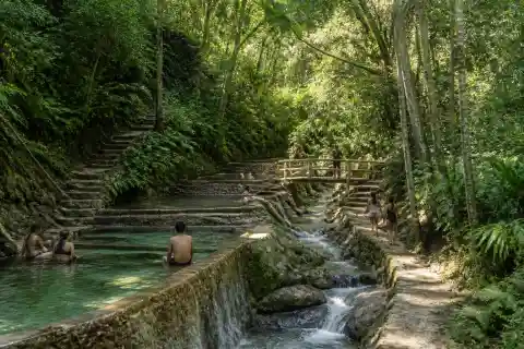 Shaded terraced spring-fed pools and stone path at Forest Camp Valencia