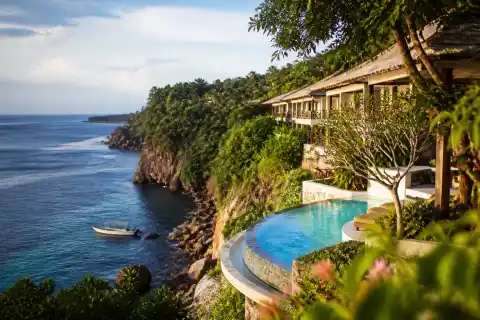 Cliffside resort with infinity-style pool overlooking Sarangani Bay and a small dive boat near the rocky shore