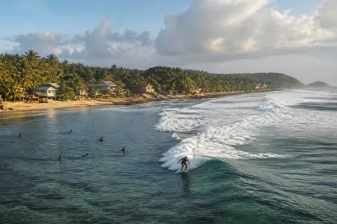 Pacifico Beach shoreline with waves and surfers, Siargao