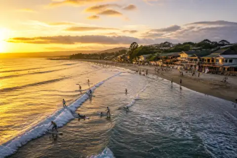 Surfers and beachfront cafés at Urbiztondo (San Juan) beach at sunset