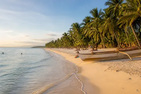 Gumasa Beach coastline with coconut palms and a small banca in Sarangani Bay
