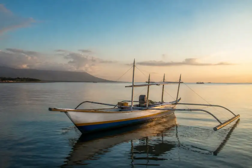 Small outrigger boat at dawn off the Donsol coast