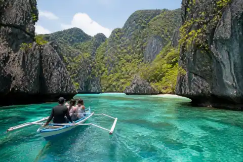 Small banca near limestone cliffs and turquoise lagoon in Palawan