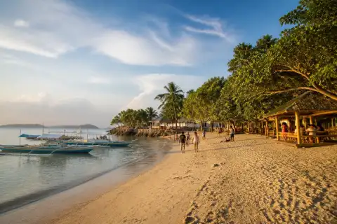 Sandy shoreline at Alubihod Beach with small resorts and boats offshore